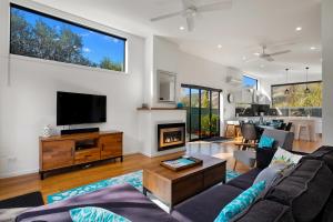 sala de estar con sofá, TV y chimenea en Kawerau River Retreat - Cromwell Holiday Home, en Cromwell