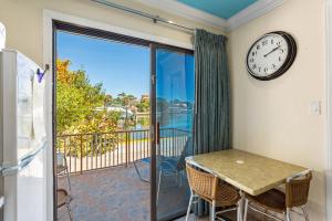a dining room with a clock and a balcony with a table and chairs at Bayview Plaza Waterfront Resort in St Pete Beach