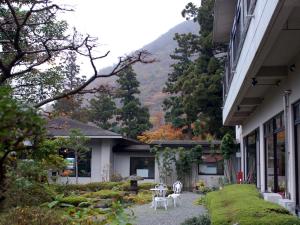 een huis met twee stoelen en een tafel in een tuin bij Kinokuniya Ryokan in Hakone