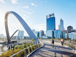 una persona che va in bicicletta su un ponte sopra una città di Citadines St Georges Terrace a Perth