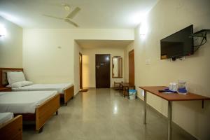 マイソールにあるKSTDC Hotel Mayura Hoysala, Mysoreのベッド2台、薄型テレビが備わるホテルルームです。