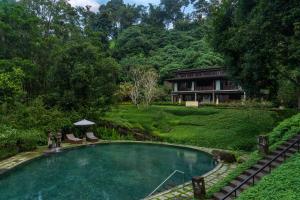 a swimming pool in front of a house at Dua Dari, a Residence by Hadiprana in Ubud