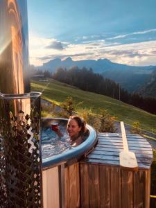 Una donna è in una vasca idromassaggio in una montagna di Boutique Chalet Panoramic Views Hot Tub a Vers L'Eglise