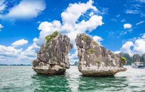 two large rocks in the water with a boat at An Ph&uacute; Hạ Long Luxury Hotel in Ha Long