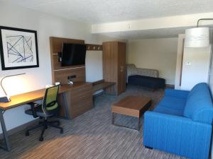 ein Hotelzimmer mit einem Schreibtisch und einem blauen Sofa in der Unterkunft Holiday Inn Express Murrysville - Delmont, an IHG Hotel in Delmont