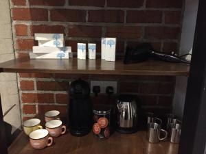 a shelf against a brick wall with cups and coffee makers at Little Kampung Studio in Teluk Intan