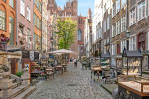 a cobblestone street with tables and chairs in a city at Downtown Apartments Old Town Mariacka in Gdańsk