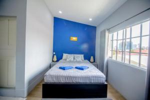 a blue bedroom with a bed with a blue wall at The Artist Residence in Phnom Penh