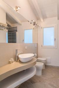uma casa de banho com um lavatório, um WC e um espelho. em Controvento em La Maddalena