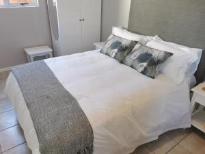Una cama blanca con dos almohadas encima. en 65at3rd, en Newton Park