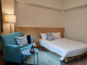 台中市にあるHotel Huru Houseのベッドルーム1室(ベッド1台、青い椅子付)