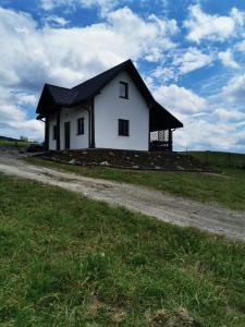 une petite maison blanche sur une colline dans un champ dans l'établissement Czadzia Przystań, à Czarna