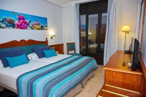 a bedroom with a bed and a desk and a television at Hotel Zentral Center - Adults only in Playa de las Americas