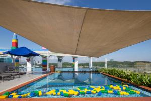 a swimming pool with chairs and an umbrella at Legoland Malaysia Hotel in Nusajaya