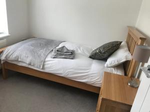 een bed met witte lakens en kussens in een kamer bij No 4 Elizabeth Street in Congleton