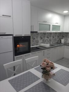 a white kitchen with a vase of roses on a table at Carev Dvor in Vrdnik