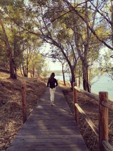 una persona caminando por un camino de madera cerca del agua en Ambroz y Plata, en Aldeanueva del Camino