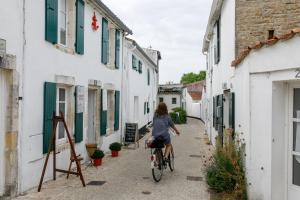 a woman riding a bike down an alley at Camping La Prée in Les Portes