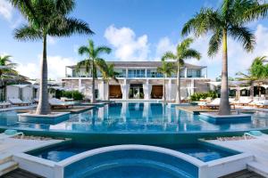 a swimming pool with palm trees in front of a building at Wymara Resort & Villas in Grace Bay