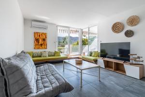 een woonkamer met een bank en een tv bij Le Canaio Upper Club par Dodo-a-Cassis in Cassis