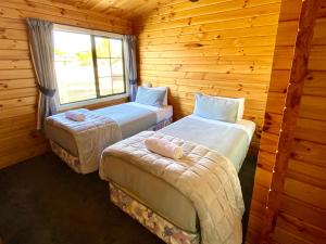 two beds in a log cabin with a window at Lockwood on Aorangi in Lake Tekapo