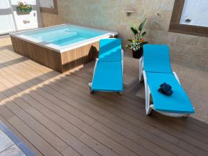 bañera de hidromasaje en una terraza con 2 sillas y piscina en Chalet Canarias en Telde