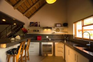 a kitchen with a sink and a counter with chairs at Bush Villas on Kruger in Phalaborwa