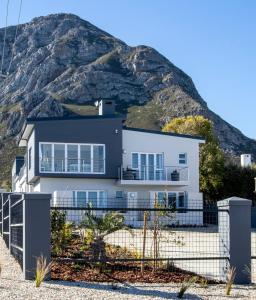 a white house with a mountain in the background at Whale Coast Ocean Villa in Hermanus