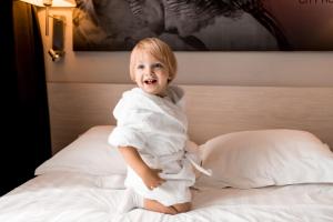 a little boy sitting on a bed in a towel at City Hotel Sova in Nizhny Novgorod