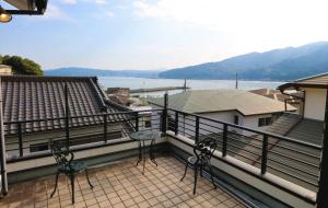 a balcony with two chairs and a view of the water at ウインザー宇佐美 in Ito