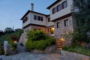 a large house with a stone wall and stairs to it at Black Diamond Luxury Unique Villa Pelion in Lafkos