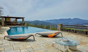 a swimming pool with two chairs and a table next to it at Black Diamond Luxury Unique Villa Pelion in Lafkos