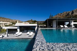 una piscina con sedie bianche e una casa di Black Diamond Luxury Beachfront Villa Selenia a Sounio