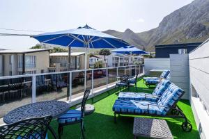 a balcony with chairs and tables and an umbrella at Whale Coast Ocean Villa in Hermanus