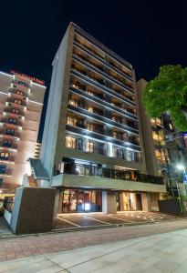 wysoki budynek w nocy z oświetleniem w obiekcie MK Hotels Nishinakasu w mieście Fukuoka