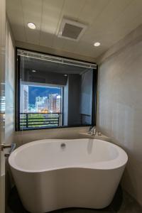 eine weiße Badewanne in einem Badezimmer mit Fenster in der Unterkunft MK Hotels Nishinakasu in Fukuoka