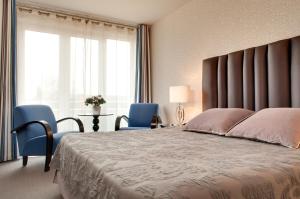- une chambre avec un grand lit et deux chaises bleues dans l'établissement Grand Hôtel de Solesmes - Teritoria, à Solesmes