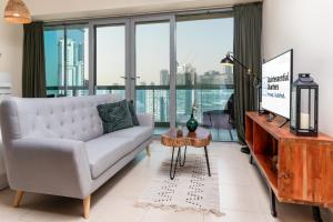 a living room with a couch and a tv at Quintessential Quarters - Gorgeous Sunset View in the Heart of Downtown in Dubai