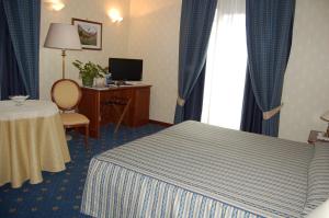 a hotel room with a bed and a table and a window at Hotel Olympic in Saint Vincent