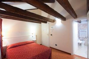 a bedroom with a red bed and a bathroom at Venice Resorts Guest House in Venice