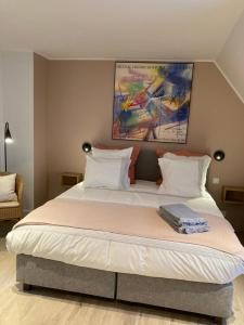 a large bed in a bedroom with a painting on the wall at B&B Waterput 1 in Stalhille