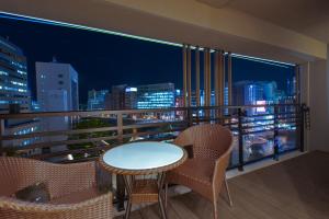 einen Balkon mit einem Tisch und Stühlen sowie einer Skyline der Stadt in der Unterkunft MK Hotels Nishinakasu in Fukuoka