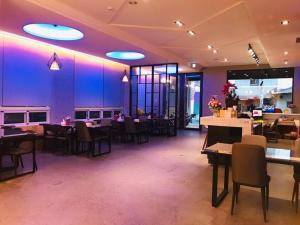 a restaurant with tables and chairs and purple lighting at Travel Light Hotel in Puli