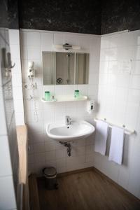 a bathroom with a sink, toilet and mirror at Hotel Charlton in Hannover