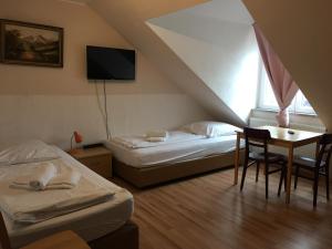 a room with two beds and a table and a tv at Pension Alis Augsburg Lechhausen Neueröffnung in Augsburg