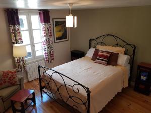 a bedroom with a bed and a chair and a window at Auberge Henri IV in Ségur-le-Château