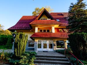 a house with a red roof and stairs leading to it at Apartamenty Miluchna in Zakopane