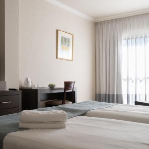 a hotel room with two beds and a desk at Kfar Maccabiah Business & Sport Hotel in Ramat Gan