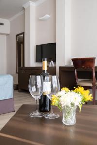 a table with two wine glasses and a vase of flowers at Kfar Maccabiah Business & Sport Hotel in Ramat Gan