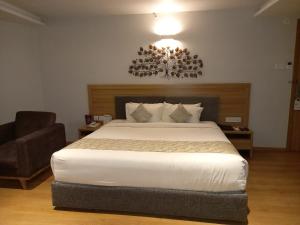 a bedroom with a large white bed and a chair at Native INN By Heda Hospitality in Belgaum